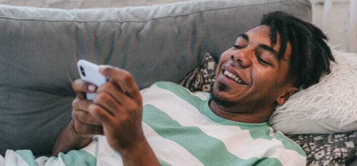 A man using a smartphone while lying on the sofa 