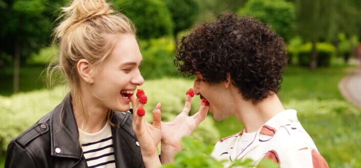 A playful couple eating raspberries