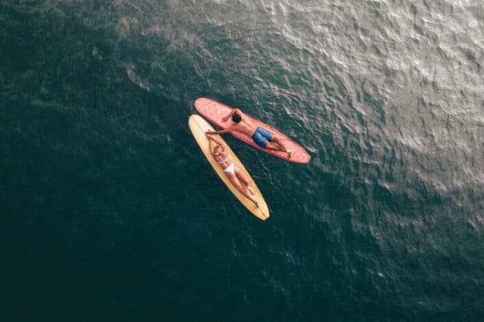 couple lying on their surfboard atop water