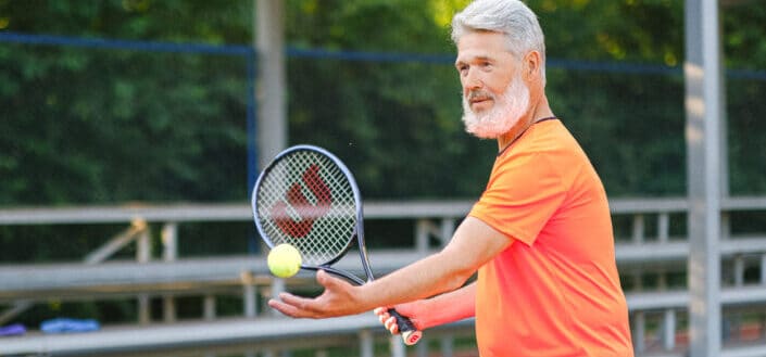 Aged tennis player with ball and racket