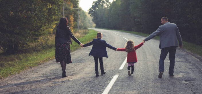Family holding hands walking on the road
