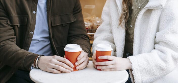 Cheerful couple drinking hot coffee in cafe