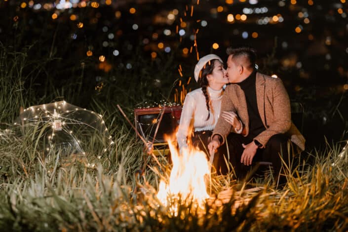 Cheerful couple kissing in nature near bonfire