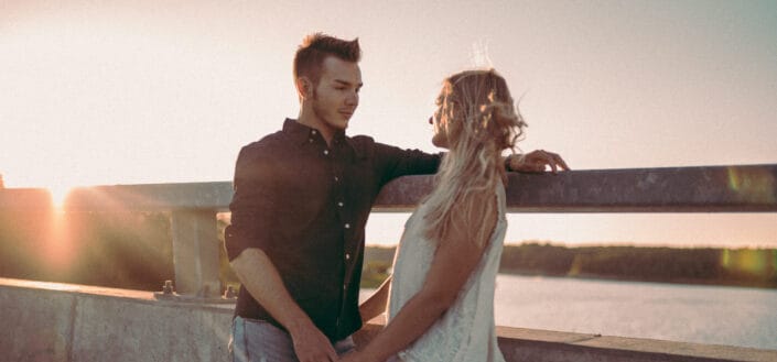 Couple standing on a bridge under the sunset