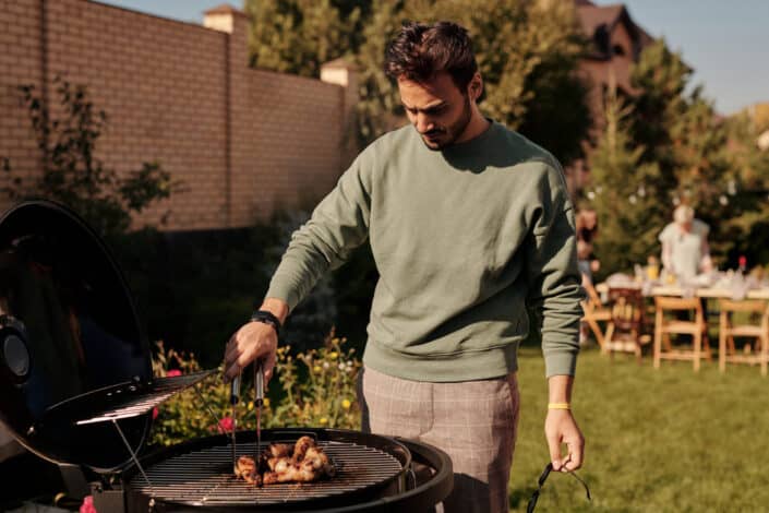 a man grilling chicken in his backyard