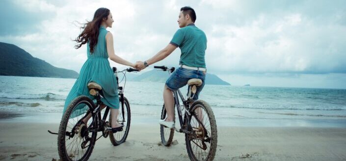 Couple riding on a bicycle in the beach