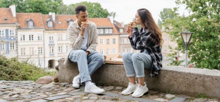 Couple eating pizza together outside