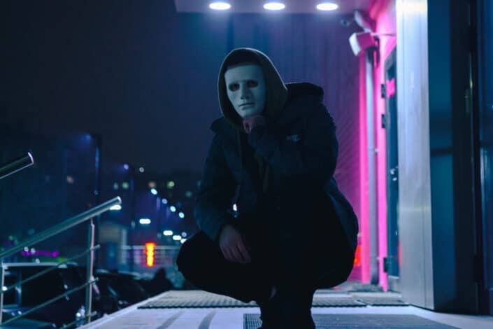 Crouching man wearing black hoodie at night