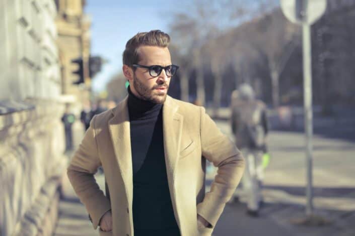 Man in a casual blazer and black turtle neck walking along the side walk