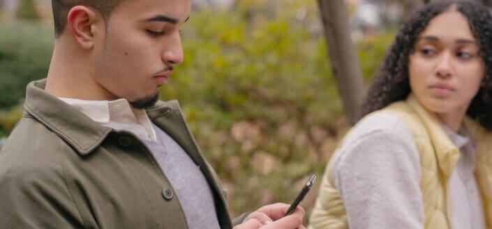 Hispanic lady looking jealously at boyfriend while texting on cellphone