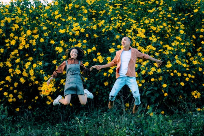 Man and woman jumping near blooming flowers