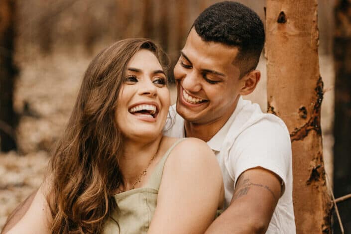 Joyful couple embracing near tree