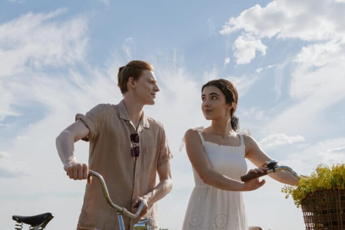 Young couple walking while holding their bikes under a clear sunny day