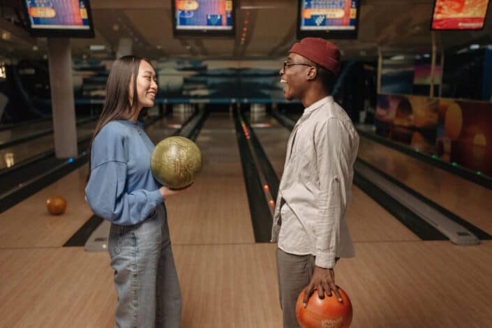 Man and woman holding bowling ball while talking