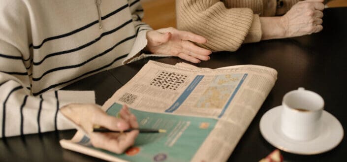 Guy answering crossword puzzle on a newspaper 
