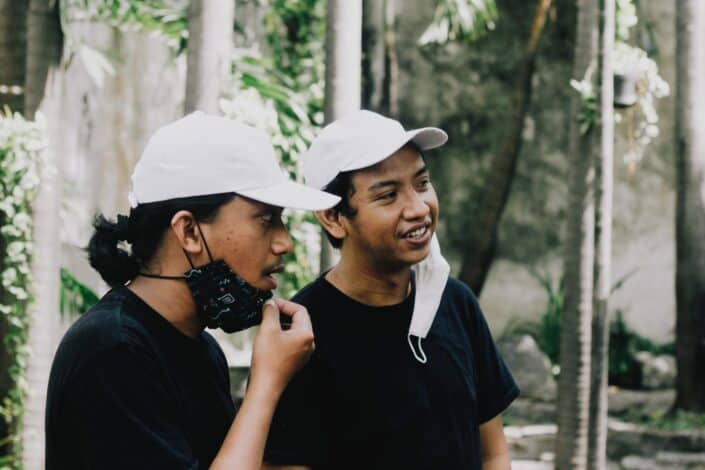Two guys in white cap and black shirt looking at something