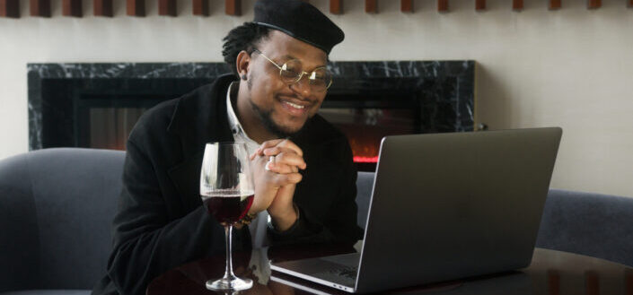 Man in black jacket sitting in front of a laptop computer