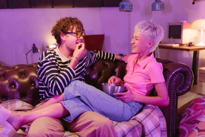 man and woman eating on sofa