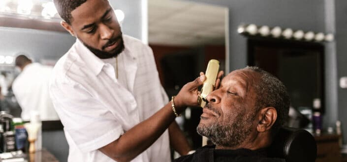 Barber shaving a man's beard