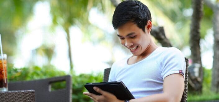 Man smiling while browsing on his tablet