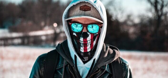 Man hiding his face with a sunglasses and skull designed facemask