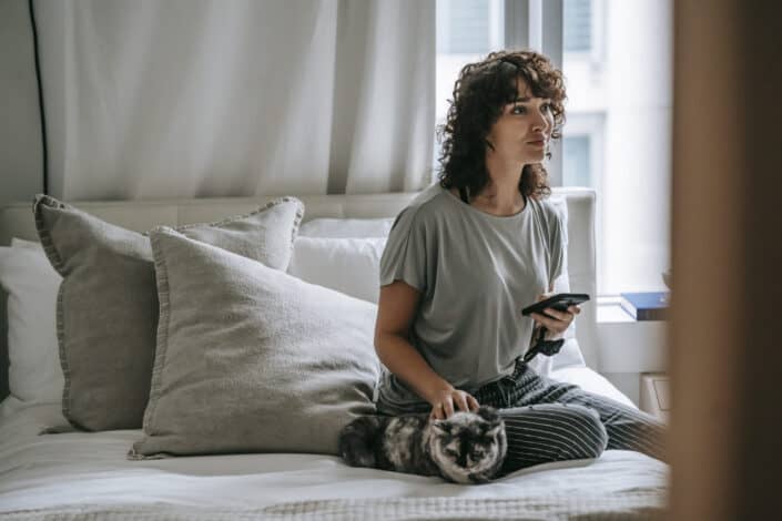 Young lady holding phone while on bed