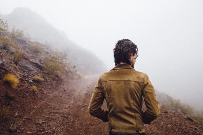 Man walking down a foggy hill