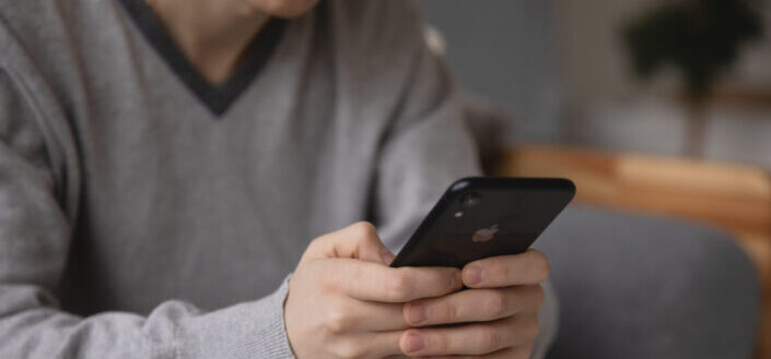 Man wearing gray cardigan checking his phone