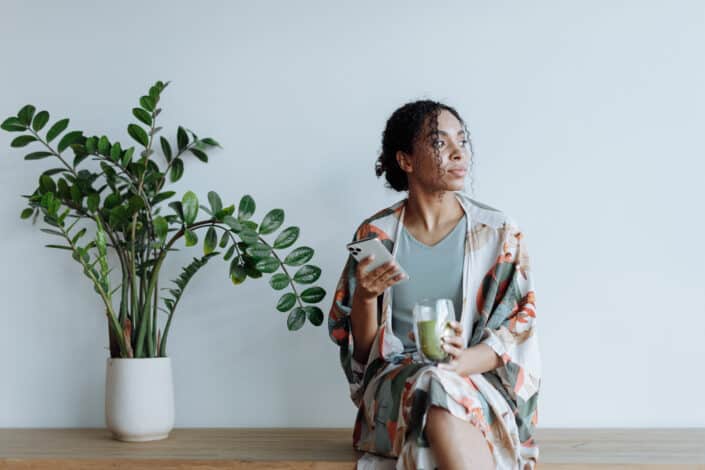 Woman sitting beside an indoor plant