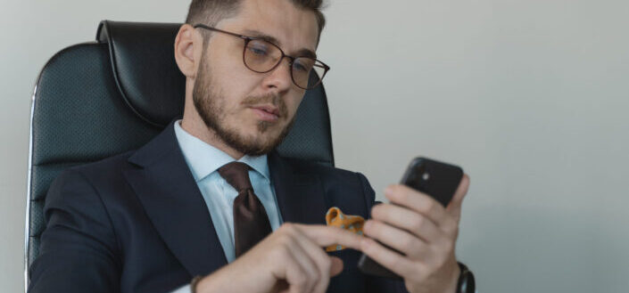 Guy wearing formal wear checking his phone 