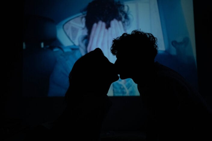 Man and woman kissing while watching movie