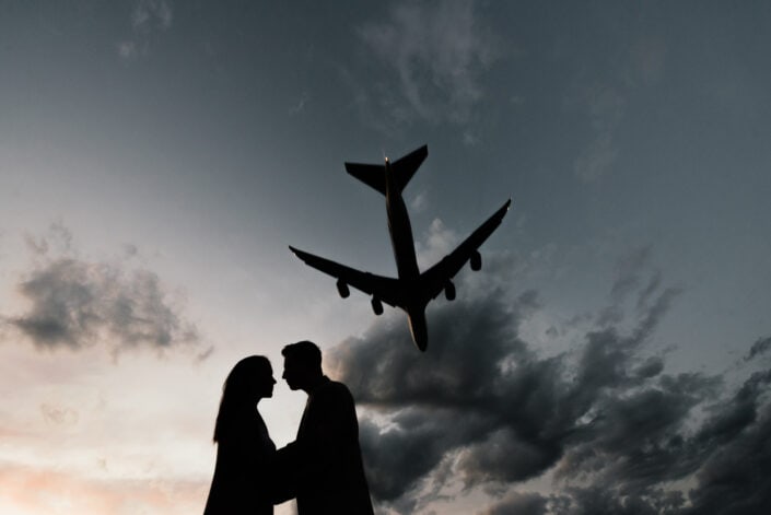 Silhouette of sweet couple with an airplane flying across the sky