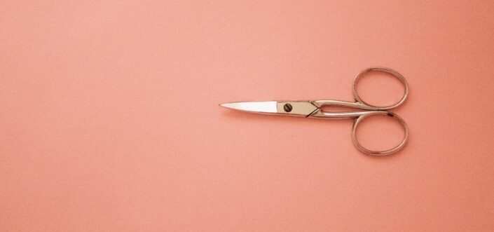 silver scissors on pink surface