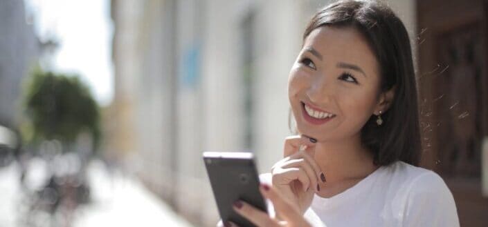 Smiling woman in white shirt holding smartphone