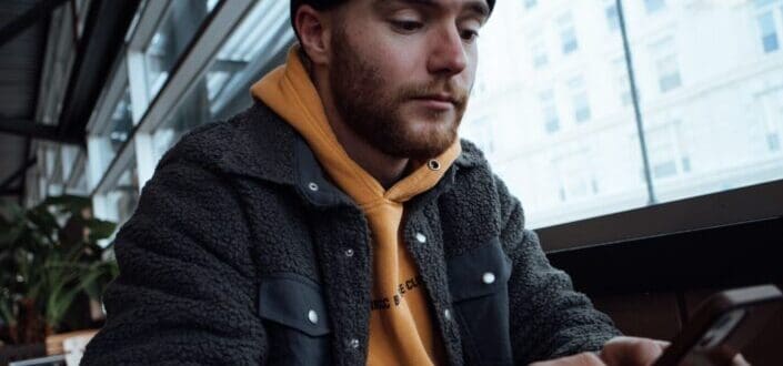 Guy sitting on a waiting area while checking on his phone