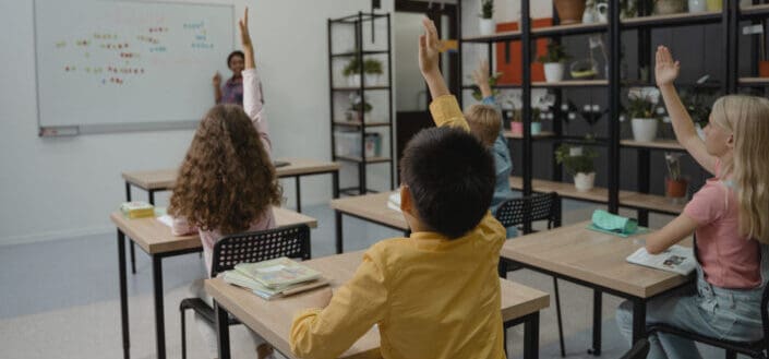 Students in class with their hands raised