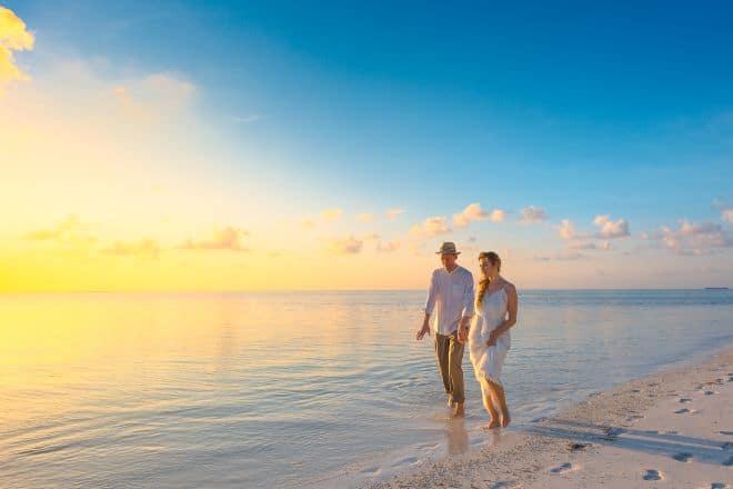 couple walking on seashore during sunset - Summer Date Ideas