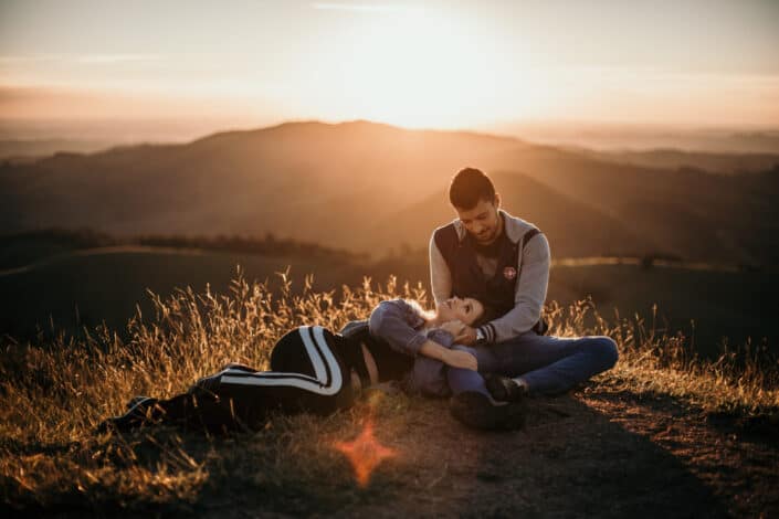 Sweet couple sitting on ground during sunset