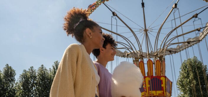 Teenage couple walking by big carousel