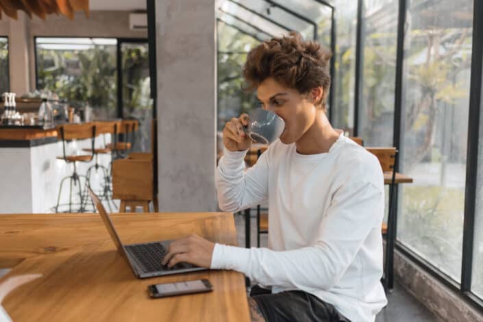 Woman drinking coffee while using laptop