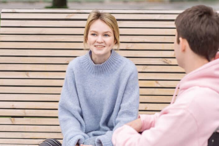 Woman sitting on bench while talking to a man on a wheelchair