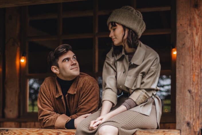 Woman sitting on railing and man standing beside her