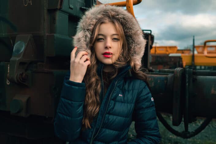 Young woman in warm clothes standing near an old rusted train