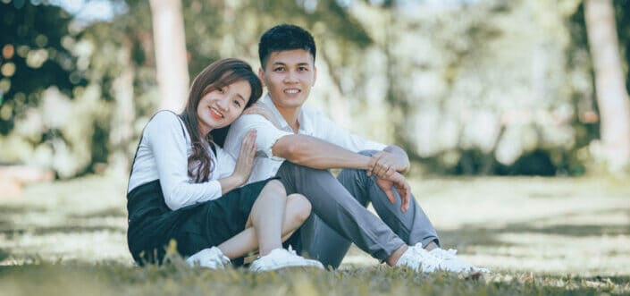 A Couple Smiling While Sitting on Grass