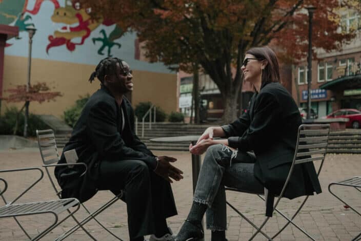 A man and woman sitting on a park while having a conversation