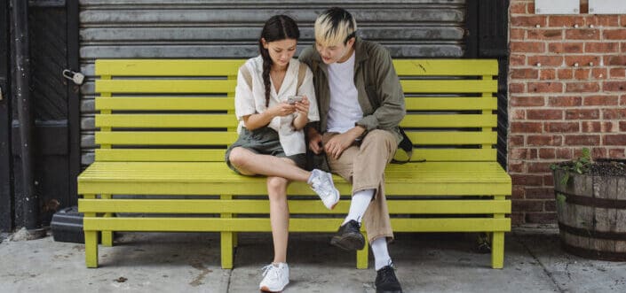 Friends Sitting on the Bench Using Smartphone