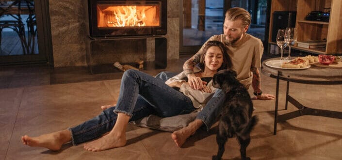 Couple With Dog Sitting Beside the Fireplace