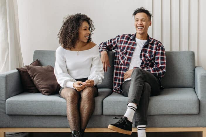 Man and woman sitting on a gray sofa