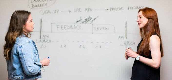 women talking beside whiteboard