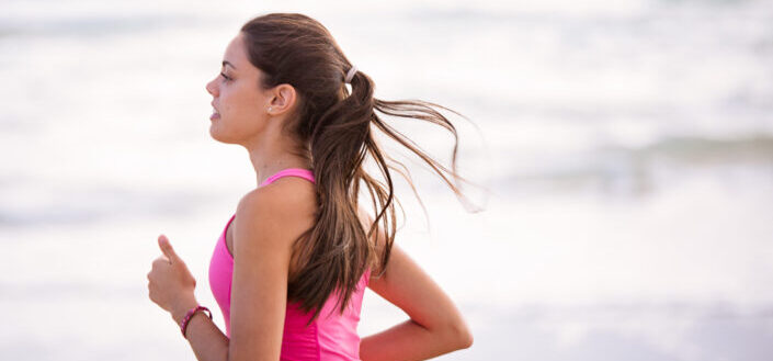 Lady in pink sports wear running on a beach side